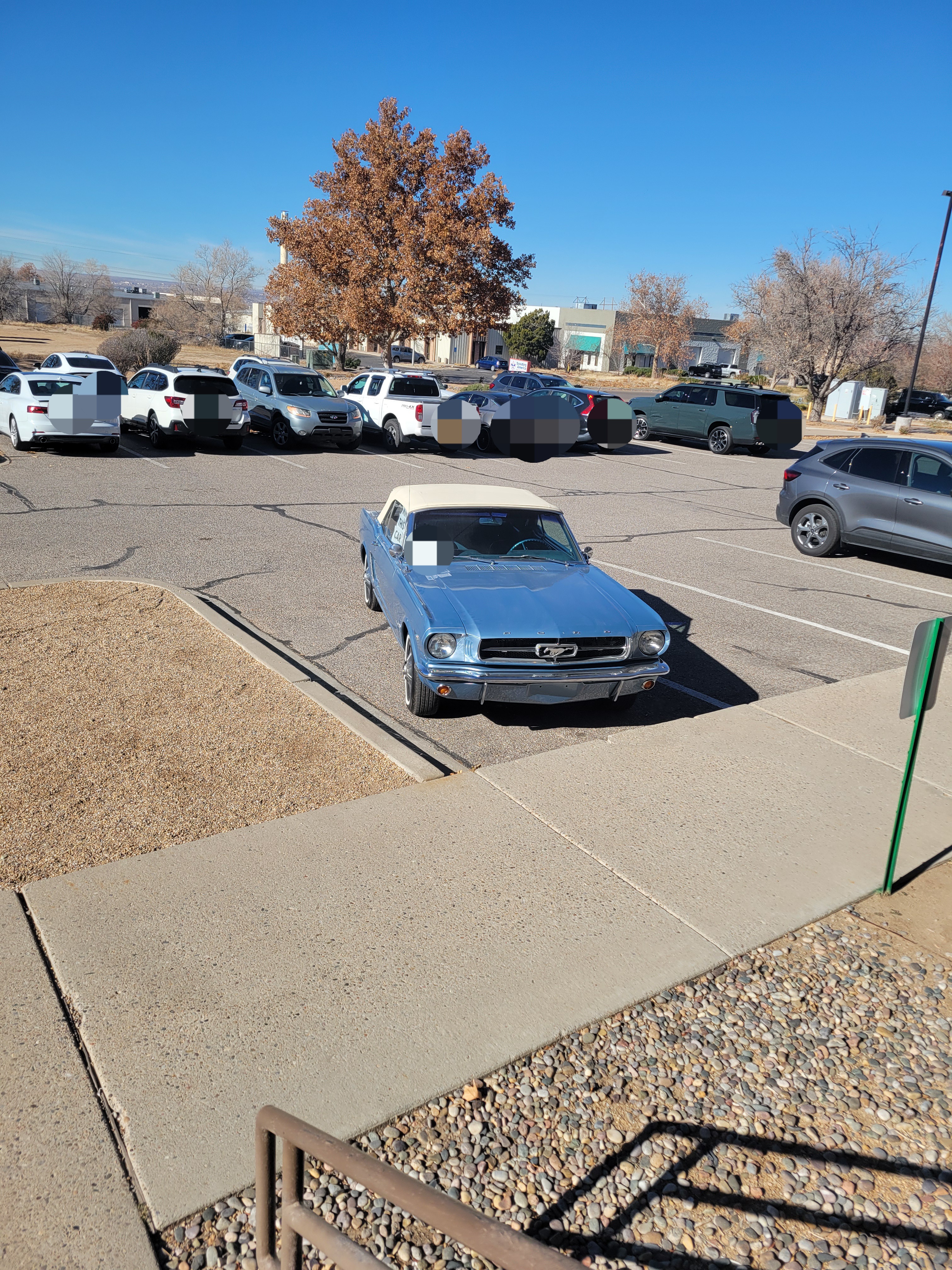 1965 blue convertible Mustang in a parking lot.
